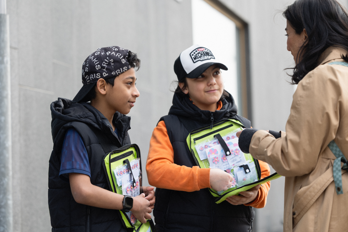 Kvinna som köper majblommor av barn. 